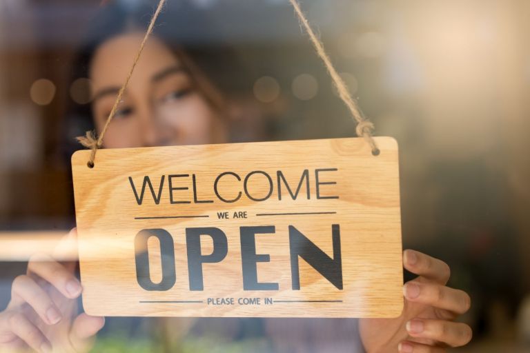 Commercant installant la pancarte ouvert a l entree de sa boutique, illustration du bail derogatoire